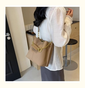 Detail of khaki bucket bag with lychee grain leather, gold chain, and FASHION & BAG strap