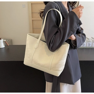 Detail of cream oversized tote bag showing pleated texture and slim shoulder straps