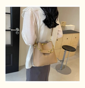 Brown bucket bag in textured leather with gold chain detail shown on a model
