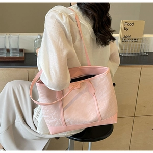 Close-up of pink textured tote bag with reinforced leather straps in a cafe setting