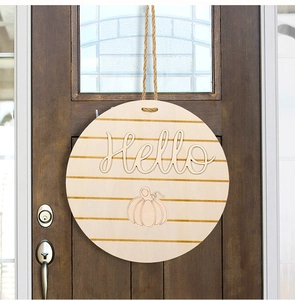 Macro detail of a wooden round door hanger with 3D Hello text and pumpkin engraving