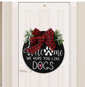 Detail of wooden welcome dog door sign with red plaid bow and green foliage on white door