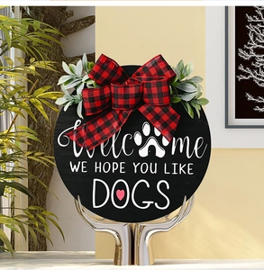 Detail of wooden welcome sign with buffalo plaid bow and greenery for dog lovers