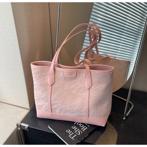 Detail of light pink tote bag featuring unique pleated texture and metal logo plaque