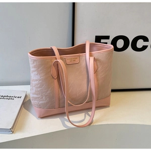 Close-up of pink tote bag with pleated texture and gold brand logo plate on the front