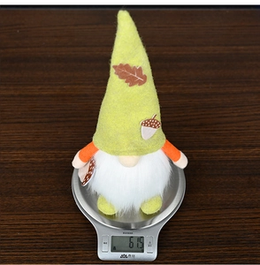 Macro shot of a fall harvest gnome plush on a digital scale showing a weight of 61.5g