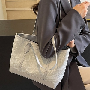 Minimalist light grey tote bag with pleated texture shown as a stylish shoulder bag