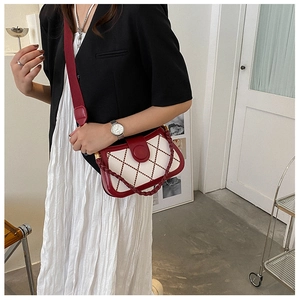 Rote und weiße Stepptasche mit gewebtem Griff und breitem Riemen am Model getragen