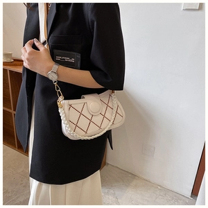Detail der cremefarbenen Stepptasche mit braunem Karomuster und geflochtenem Griff