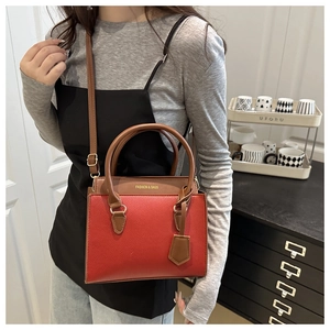 Detailopname van rode leren tas met contrasterende bruine flap en gouden gespen