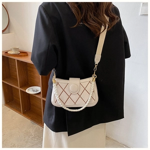 Detailaufnahme der cremeweißen Stepptasche mit goldenen Beschlägen und Kettenriemen