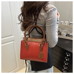 Detail of red and brown contrast shoulder bag with pebble grain texture and top handle