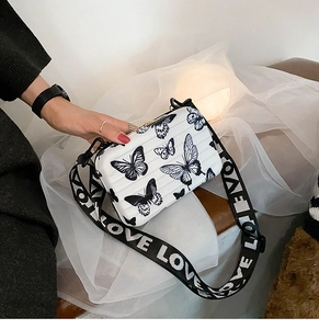 Detail of white butterfly print box bag featuring wide LOVE lettered strap and zipper closure