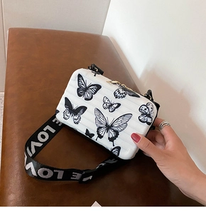 Detail of white butterfly hardshell crossbody box bag with wide LOVE letter strap
