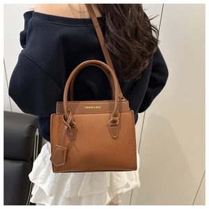 Detail van de karamelbruine leren schoudertas met FASHION & BAGS logo-opdruk
