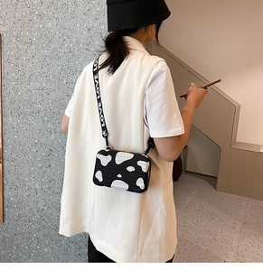 Detail of a cow print box bag featuring a wide strap with white LOVE text