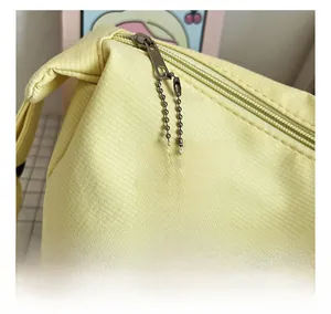 Detail of yellow canvas tote bag featuring silver metal zipper and cute cartoon charm