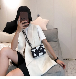 Detail of a cow print crossbody bag with a wide black strap featuring LOVE lettering