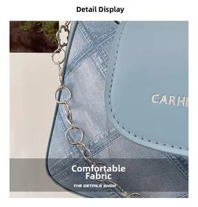 Detail of light blue denim texture shoulder bag with silver chain and CARHE hardware