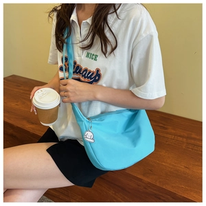Close-up of light blue nylon crescent bag with a cute white cartoon dog charm