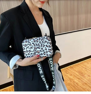 Detail of leopard print crossbody bag with wide LOVE strap and gold metal double zippers