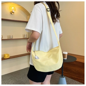 Detail of light yellow crescent canvas bag with adjustable strap and cloud charm