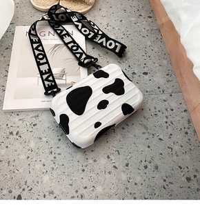 Detailed macro view of a mini suitcase bag featuring cow print patterns and LOVE strap