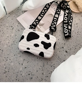Detailed view of mini suitcase crossbody bag with cow pattern and LOVE wide strap