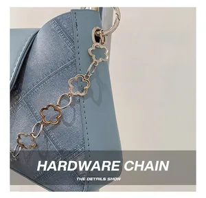 Detail of light blue crossbody bag with unique floral hollow-out hardware chain strap