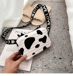 Detail of cow print suitcase bag featuring a wide strap with LOVE lettering