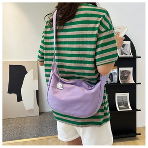 Detail of purple crescent hobo bag with a cute cartoon charm on a nylon shoulder strap