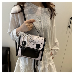 Detail of pink embroidered handbag with black bows and lace pearl charm accessory