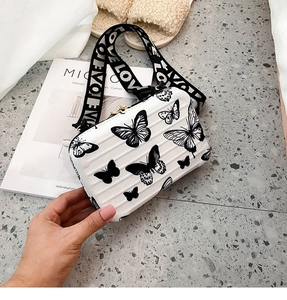 Close-up of white hardshell box bag with butterfly prints and LOVE wide shoulder strap