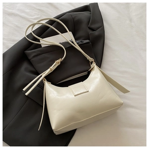 Close-up of minimalist cream crescent underarm bag with smooth leather and metal buckles
