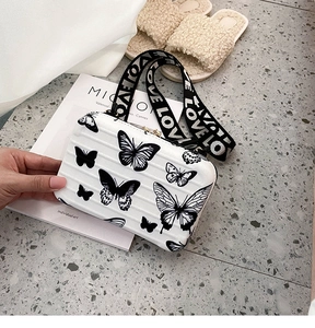 Close-up of white mini hard-shell crossbody bag with butterfly prints and LOVE strap