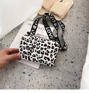 Detail view of leopard print box bag with wide logo strap and hard shell design