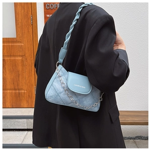 Detail of light blue leather underarm bag with decorative metal flower chain