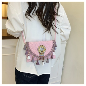 Close-up of pink woven straw crossbody bag with colorful beadwork and layered tassels