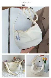 Detail of off-white canvas crescent bag with adjustable strap and cute dog pendant