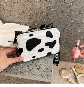 Detail of a mini suitcase bag with cow print texture and a LOVE letter fabric strap