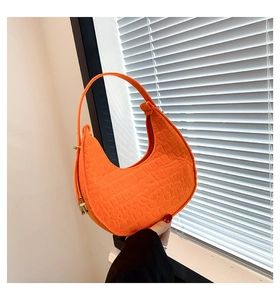 Detailed view of crocodile embossed orange half-moon shoulder bag with golden buckle
