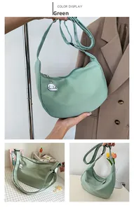 Detail of green nylon crescent shoulder bag featuring adjustable strap and cloud charm