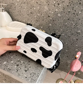 Stylish cow print suitcase-style mini crossbody box bag shown in close-up detail.