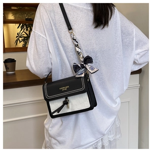 Detail of crossbody bag featuring printed silk scarf strap and leather tassel accent