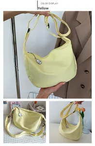 Detail of yellow canvas crescent bag with adjustable strap and cartoon charm accent