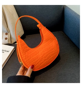 Detail showing bright orange faux crocodile leather texture on crescent shoulder bag