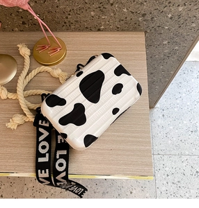 Detail of mini suitcase crossbody bag with cow print pattern and LOVE lettered strap