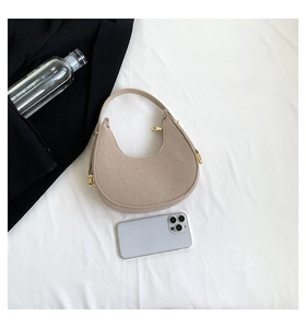 Detail of beige felt half-moon shoulder bag with gold zipper on white fabric