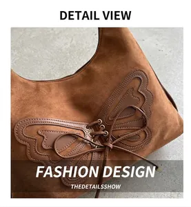 Détail du sac croissant en daim marron avec applique papillon en cuir et design à lacets
