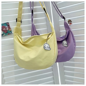 Detail of yellow and purple half-moon canvas bags with cute dog charms and strap